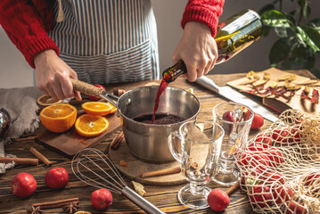 Woman is pouring wine to cook mulled wine. Process of making a warming traditional beverage, a cozy festive atmosphere