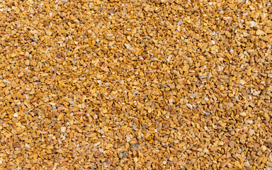lose up of small stone texture. Abstract background of decorative floor, pebble stones. Gravel, yellow-orange road in the park.