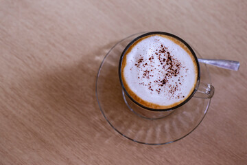 Hot coffee with frothed milk sprinkled with cocoa powder from top view