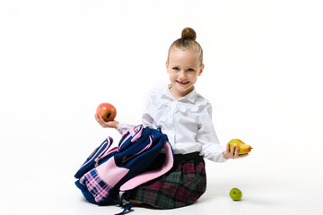 Cute girl in school uniform with a backpack and apples on a white background.