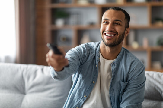 Portrait Of Cheerful Young African American Man Watching TV At Home