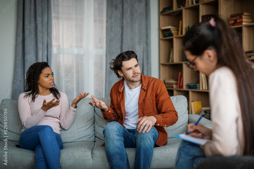 Wall mural Offended dissatisfied angry emotional millennial different husband and wife swear at meeting with psychologist