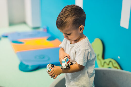 Imagination and creative thinking development. Toddler boy playing with car toys in a nursery school playroom. High quality photo