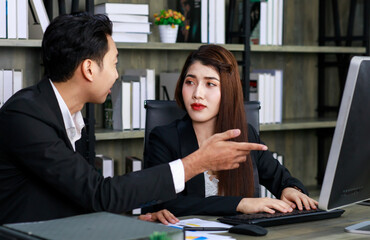 Millennial Asian young professional successful female businesswoman ceo entrepreneur in formal suit sitting smiling working via computer while male businessman secretary helping writing note on paper