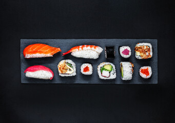 Sushi set on a black slate  background. Japan restaurant menu. Sushi with salmon, tuna and avocado. Top view.