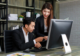 Millennial Asian young professional successful male businessman ceo entrepreneur in formal suit sitting looking reading checking paperwork document in folder from female businesswoman secretary