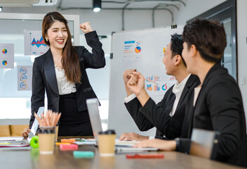 Asian young beautiful professional successful businesswoman presenter standing smiling in front of glass board after presenting while male female colleagues clapping hands thank you in meeting room