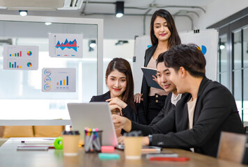 Asian young beautiful professional successful businesswoman mentor standing smiling pointing computer coaching teaching strategy to group of male and female businesspeople colleagues in meeting room