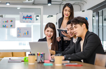 Asian young beautiful professional successful businesswoman mentor standing smiling pointing computer coaching teaching strategy to group of male and female businesspeople colleagues in meeting room