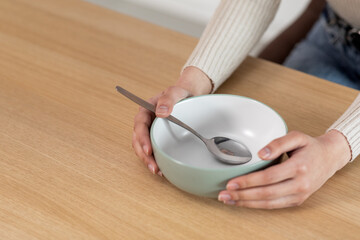 Cropped of woman holding empty plate with spoon in it
