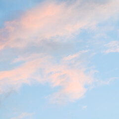 Blue sky background with pale pink clouds at sunset
