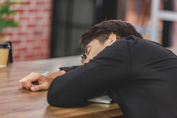 Asian young tired exhausted businesswoman in formal suit sitting napping on table while male female businesspeople colleagues closed eyes take break sleeping together after working late overtime