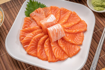 Sliced ​​Fresh Salmon white plate on wooden background, Salmon sashimi salmon sashimi with sauce and wasabi reday to eat.