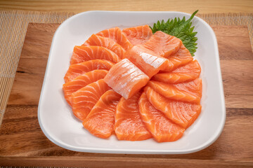 Sliced ​​Fresh Salmon white plate on wooden background, Salmon sashimi salmon sashimi with sauce and wasabi reday to eat.