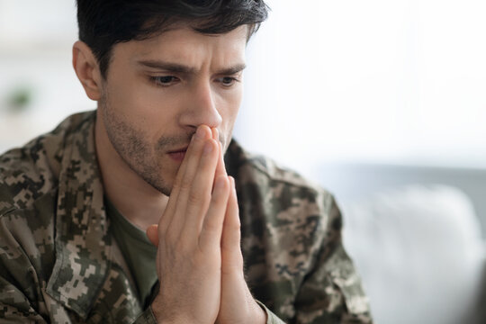Serious young man soldier having thoughts of suicide