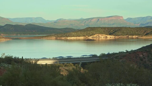 Lake and Mountains. Beautiful sunset at Theodor Roosevelt Lake, Panorama with car passing, crossing bridge. AZ, USA. Panorama right to left.