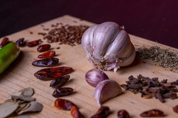 Close up on Garlic cloves on a rustic table mixed with fresh spices and herbs. 