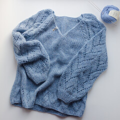 blue knitted sweater on a white background with blue threads next to it