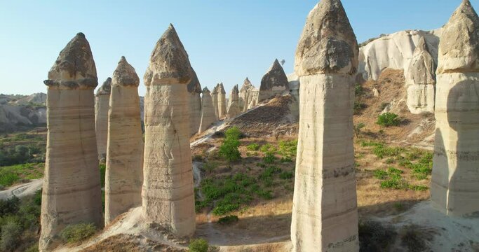 The Valley of Love in Cappadocia, Turkey. Stone Pillars. The drone flies between the pillars, a balloon is flying on the horizon. Attractions In Cappadocia