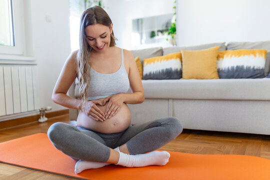 pregnant woman training yoga, caressing her belly. Young happy expectant relaxing, thinking about her baby and enjoying her future life. Motherhood, pregnancy, yoga concept