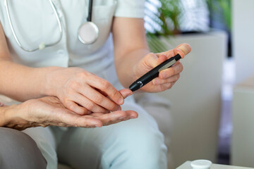 Nurse measuring blood sugar of senior woman at home. Young nurse measuring blood sugar of elderly woman at home. Doctor checking elderly woman's blood sugar - diabetes and glicemia concept