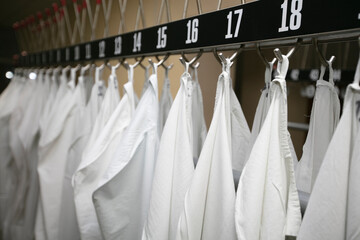 White medical gowns hang on hangers in the hospital.