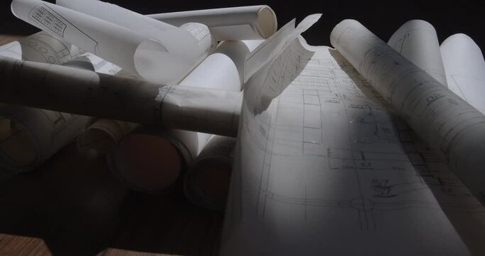 Scattered, crumpled, and damaged piles of construction plans lie on the floor in the dusk.  Camera slide movement from left to right