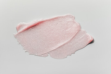 Smears of transparent pink lip gloss or moisturizer with glitter on grey background. Body highlighter swatch