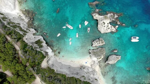 Top aerial shot of Tremiti island's beach with multiple boat sailing in the crystal blue sea 