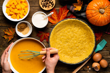 the process of making American pumpkin pie women's hands on a wooden table with ingredients, autumn food composition