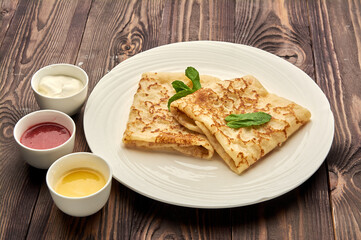delicious juicy pancakes lie on a white plate with sauces standing next to them