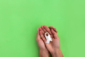Woman holding hand ribbon on green background with copy space. Mockup for world mental health day