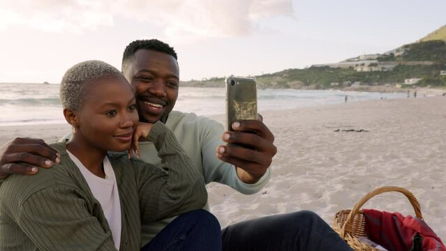 Selfie, black couple and love during a beach picnic on the sand in summer. Happy man and woman taking a picture with a phone for social media together while on a romantic leisure date by the sea