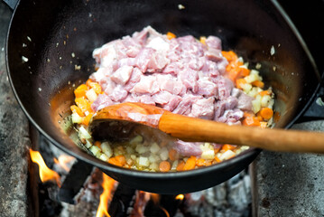 Meat and vegetables in a cauldron on fire