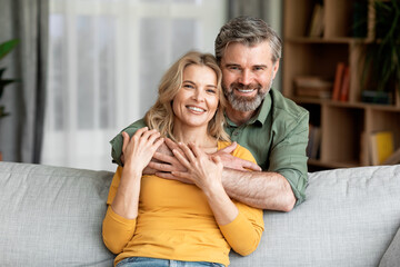 Portrait Of Smiling Middle Aged Spouses Posing In Home Interior