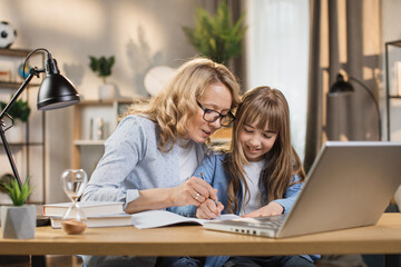 Little kid writing and sketching in notebook, with mother's encouragement and assistance. Mom and daughter, teaching and interests go hand in hand. Children's abilities inventiveness developing.