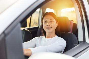 Portrait of happy woman driving a car and smiling, cute young success brunette woman driver...