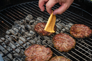 Selective focus of fresh delicious burger cutlets with cheese grilling on bbq grill