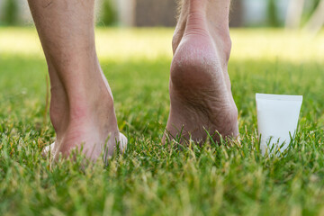 Men's heels (feet) with dry skin and scaly with cream on grass
