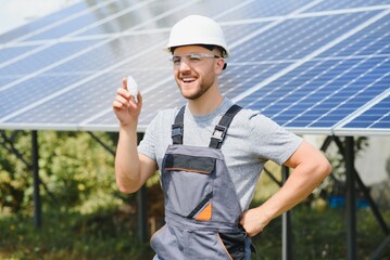 Technical expert in solar photovoltaic panels, remote control performs routine actions to monitor the system using clean renewable energy in the hand a light bulb.