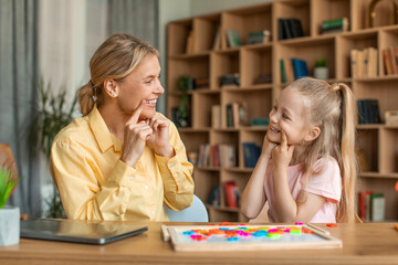 Female speech-language pathologist having lesson with little girl, teacher and pupil working on...