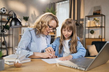 Little kid writing and sketching in notebook, with mother's encouragement and assistance. Mom and daughter, teaching and interests go hand in hand. Children's abilities inventiveness developing.