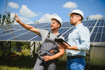 Two engineers are conducting outdoor inspection of solar photovoltaic panels