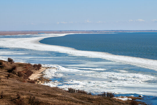 February seashore with melting ice near shore, seasonally nature landscape of coming spring