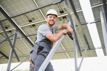 Male engineer in protective helmet installing solar photovoltaic panel system. Alternative energy...