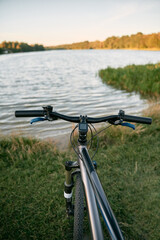 Fototapeta na wymiar Mountain bike on a lake shore. Summer sunset adventures in the countryside. Using a bicycle in rural area.