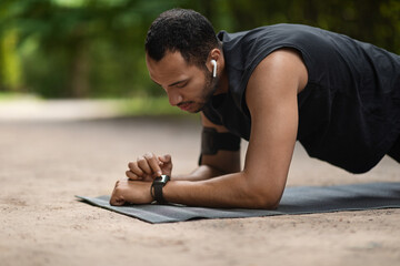 Handsome young sporty black man set his fitness tracker