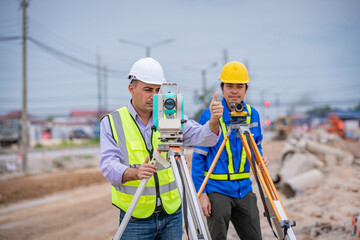 Surveyor engineer wearing safety uniform ,helmet and radio communication with equipment theodolite...