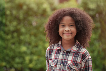 African American kid girl is smiling in the garden or outdoors.