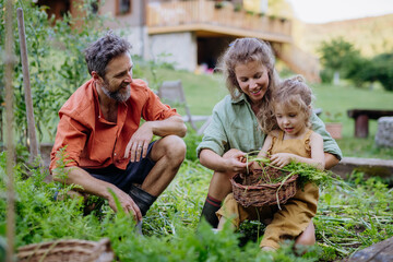 Happy farmer family with fresh harvest together in garden in summer.